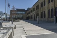 the empty street in front of the school is empty and it has benches on the curb