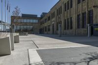 the empty street in front of the school is empty and it has benches on the curb