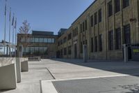 the empty street in front of the school is empty and it has benches on the curb