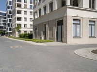 an empty paved street with a few tall buildings in the background, there are people standing around