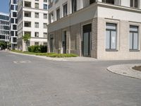 an empty paved street with a few tall buildings in the background, there are people standing around