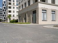 an empty paved street with a few tall buildings in the background, there are people standing around