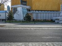 an empty street that is next to a city building on the side of it with trees in the background