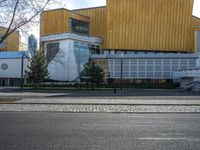 an empty street that is next to a city building on the side of it with trees in the background