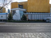 an empty street that is next to a city building on the side of it with trees in the background