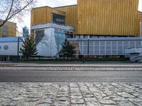 an empty street that is next to a city building on the side of it with trees in the background