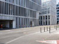 the empty street near buildings has a lot of glass windows and fencing on both sides