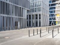 the empty street near buildings has a lot of glass windows and fencing on both sides