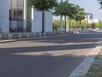 an empty street in front of some building on the other side of it with trees