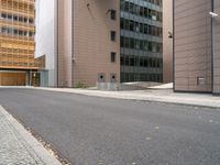 an empty street between a city and buildings with tall glass windows along both sides of the street