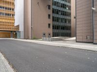 an empty street between a city and buildings with tall glass windows along both sides of the street