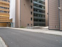 an empty street between a city and buildings with tall glass windows along both sides of the street