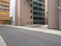 an empty street between a city and buildings with tall glass windows along both sides of the street