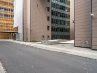 an empty street between a city and buildings with tall glass windows along both sides of the street