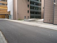 an empty street between a city and buildings with tall glass windows along both sides of the street