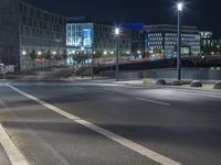 large building on the street with lights in front and other buildings nearby at night with no one moving