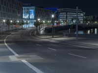 large building on the street with lights in front and other buildings nearby at night with no one moving