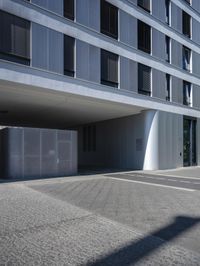 an empty street under a parking garage next to tall buildings on a sunny day with a bright sun shining through the windows