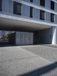 an empty street under a parking garage next to tall buildings on a sunny day with a bright sun shining through the windows