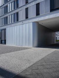 an empty street under a parking garage next to tall buildings on a sunny day with a bright sun shining through the windows