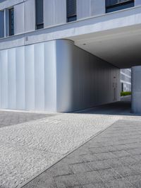 an empty street under a parking garage next to tall buildings on a sunny day with a bright sun shining through the windows