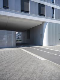 an empty street under a parking garage next to tall buildings on a sunny day with a bright sun shining through the windows