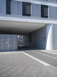 an empty street under a parking garage next to tall buildings on a sunny day with a bright sun shining through the windows