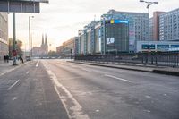 people walking across a empty street in the day time at sunrise with traffic lights on