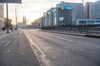 people walking across a empty street in the day time at sunrise with traffic lights on