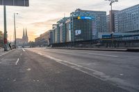 people walking across a empty street in the day time at sunrise with traffic lights on