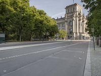 there is an empty street that has trees and a building in the background in this photo