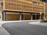 an empty paved street with a very tall building behind it in a city area with cobblestone