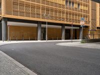 an empty paved street with a very tall building behind it in a city area with cobblestone