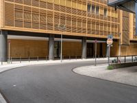 an empty paved street with a very tall building behind it in a city area with cobblestone