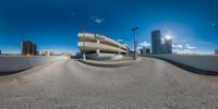 360 - angle shot of an empty street in a big city with tall buildings and large, blue sky above