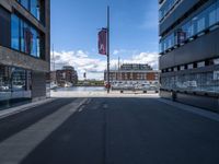 a very empty street in front of some buildings with a street flag flying in the sky