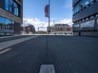 a very empty street in front of some buildings with a street flag flying in the sky