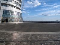 an empty street in front of a modern building with windows on top of it and cobblestone paved ground in the foreground