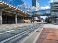 an empty street with a bridge over it next to tall buildings and a car park