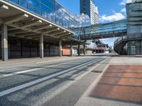 an empty street with a bridge over it next to tall buildings and a car park