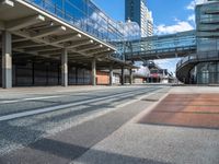 an empty street with a bridge over it next to tall buildings and a car park