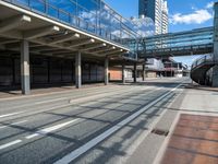 an empty street with a bridge over it next to tall buildings and a car park