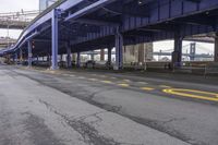 the empty street is lined with traffic and blue supports, near the brooklyn bridge bridge