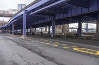 the empty street is lined with traffic and blue supports, near the brooklyn bridge bridge