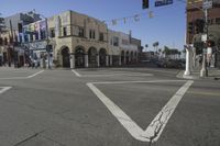 an empty street has cars and buildings in the background, with a stop light on each side of the road