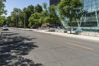 empty street with buildings along side and trees on both sides of the road in front