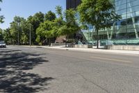 empty street with buildings along side and trees on both sides of the road in front