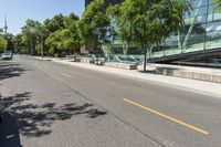 empty street with buildings along side and trees on both sides of the road in front