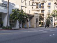 an empty street with several businesses on it and some cars going by the corner of the street