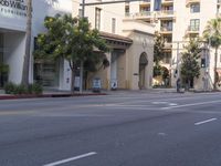 an empty street with several businesses on it and some cars going by the corner of the street